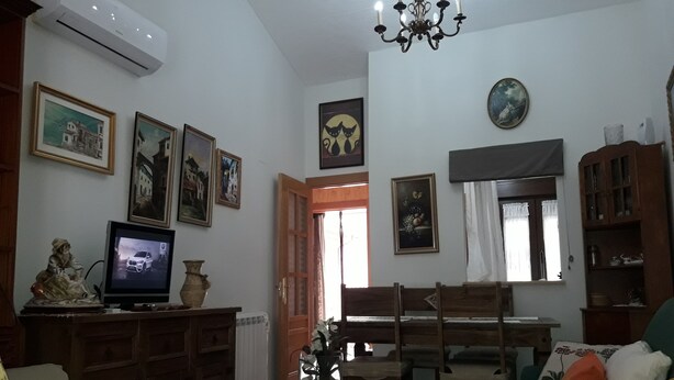 Una sala de estar con televisión, muebles de madera y varias fotografías enmarcadas en las paredes.