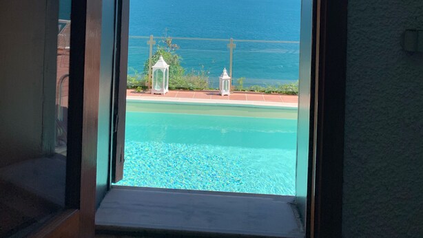 A view through an arched window of a pool and ocean. - Villa Anna with Pool and panoramic terrace. (Costa Saracena - Castelluccio)