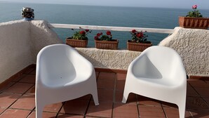 A terrace with white plastic chairs, terracotta planters with red flowers, and a view of the sea. - Villa Anna with Pool and panoramic terrace. (Costa Saracena - Castelluccio)