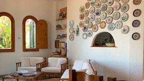 A cozy living room with a dining area, featuring a wall adorned with numerous decorative plates, a fireplace, and comfortable seating. - Villa Anna with Pool and panoramic terrace. (Costa Saracena - Castelluccio)