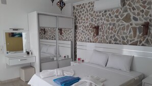 Ein Hotelzimmer mit Bett, Nachttisch, Spiegel, Kleiderschrank und einer Steinwand.