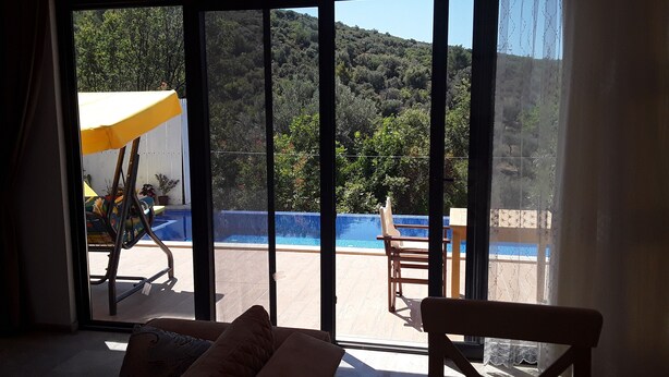 Ein Zimmer mit einer großen Schiebeglastür, die zu einem Außenbereich mit Pool und Blick auf einen bewaldeten Hügel führt.