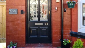 A black double door with the number 24, a small window above it, and a flower pot on the right. - VICTORIA24: CRAIG Y DON LLANDUDNO
CLOSE TO PROMENADE & VENUE  CYMRU (Llandudno)