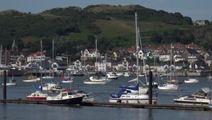 A marina with various boats docked, surrounded by residential buildings and a hilly landscape in the background. - VICTORIA24: CRAIG Y DON LLANDUDNO
CLOSE TO PROMENADE & VENUE  CYMRU (Llandudno)
