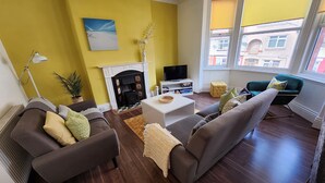 A living room with a fireplace, sofas, a television, and a view of buildings outside. - VICTORIA24: CRAIG Y DON LLANDUDNO
CLOSE TO PROMENADE & VENUE  CYMRU (Llandudno)