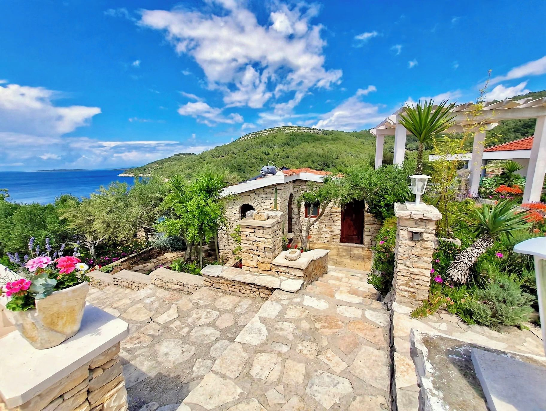 A stone pathway leading to a stone building with a view of the sea.
