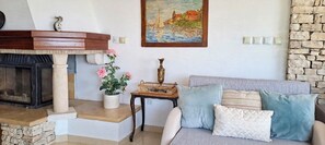 A living room with a fireplace, a painting, a stone wall, and a sofa with cushions.