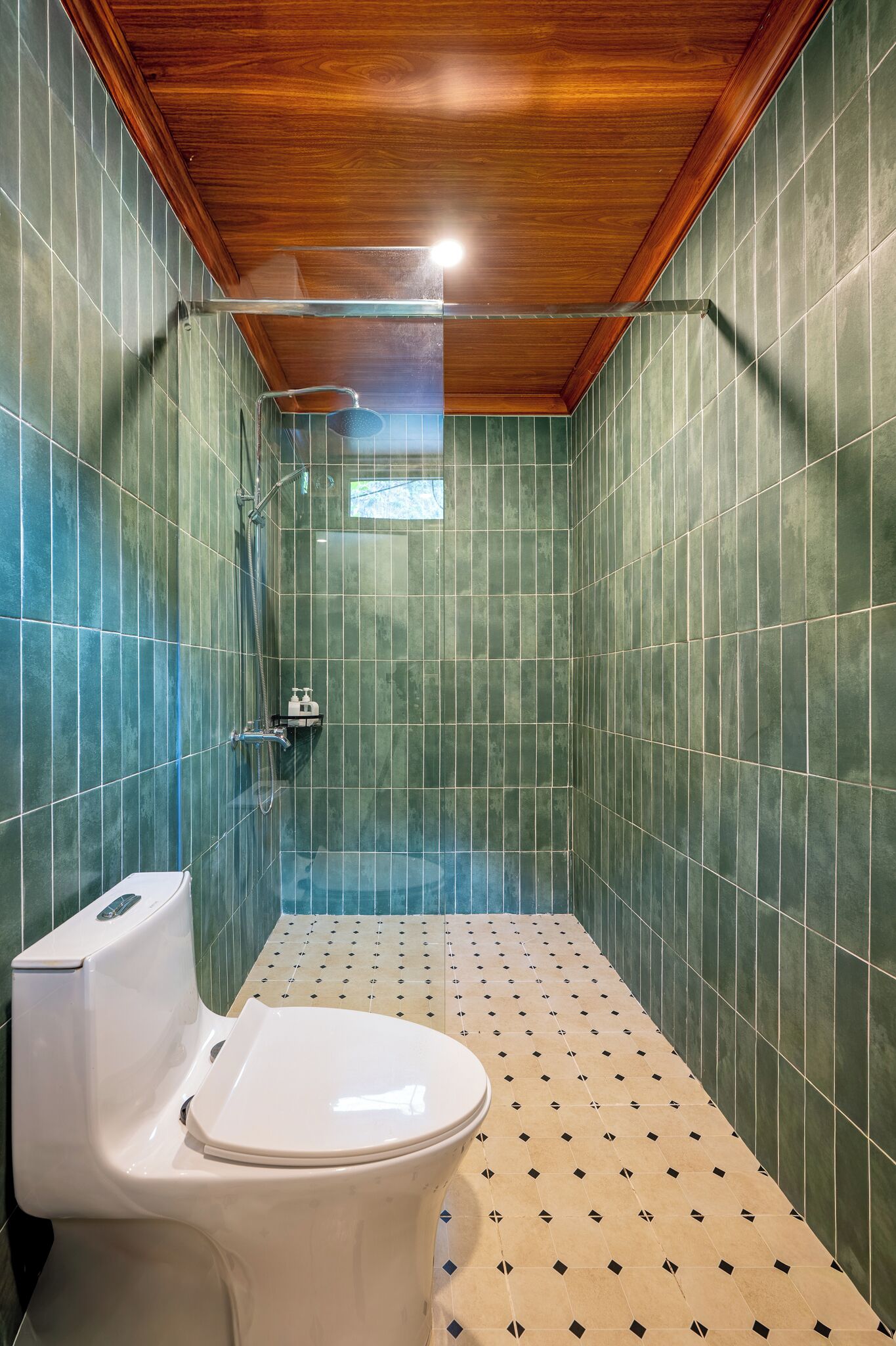 A small, enclosed shower area with a wooden ceiling and green tiled walls.