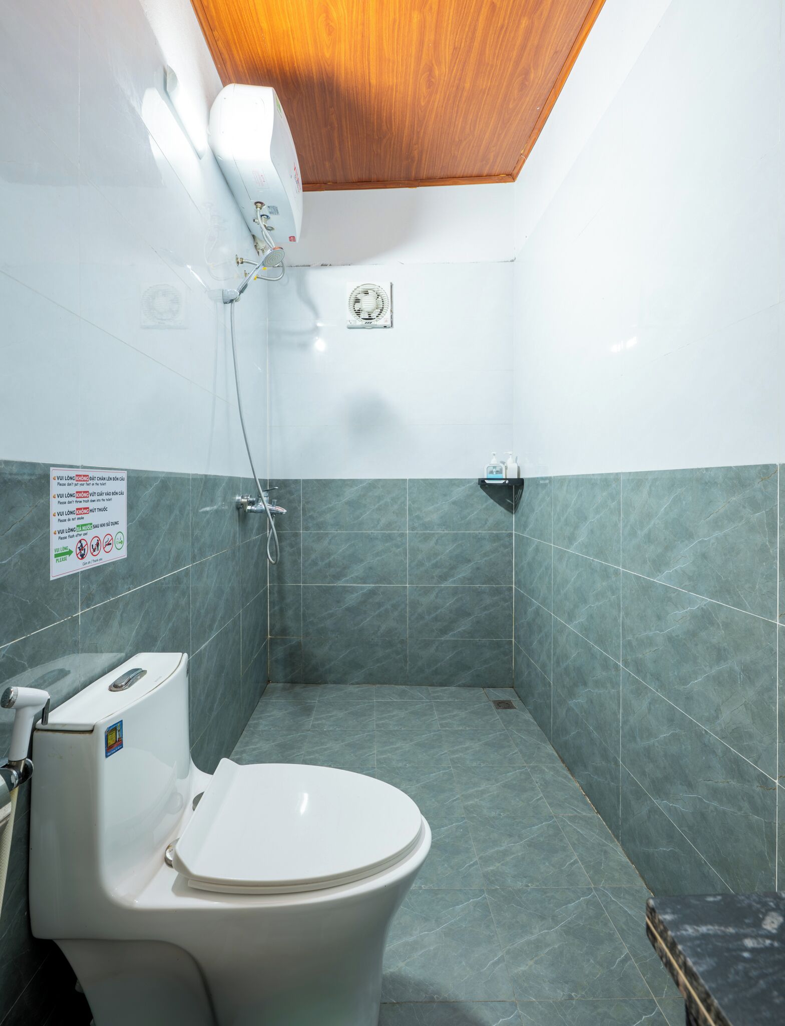 A bathroom with a toilet, a shower, and a hand dryer.