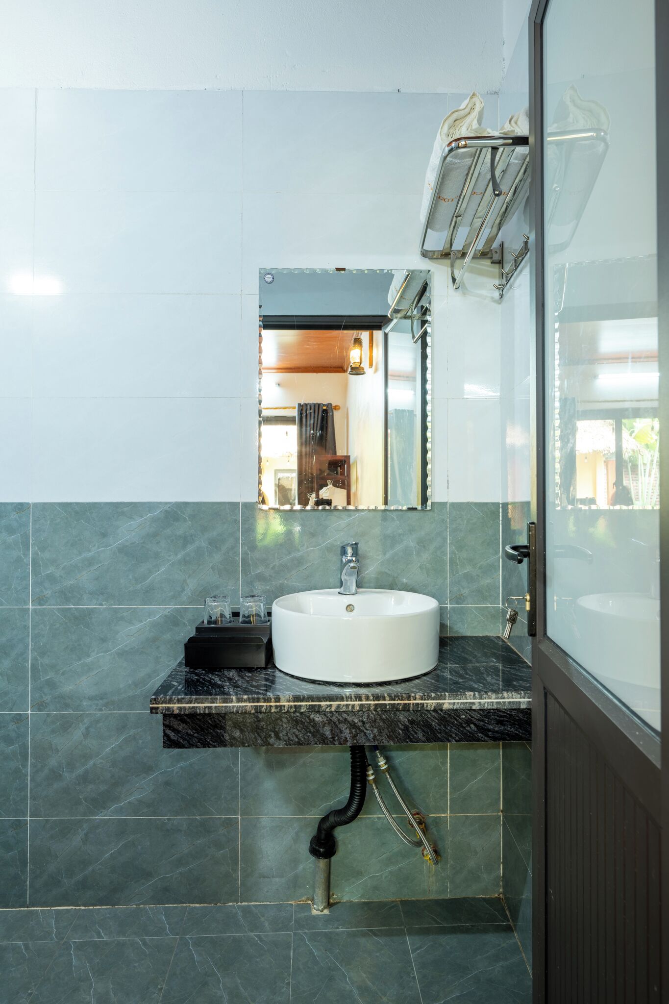 A bathroom with a white sink, dark marble countertop, and a mirror above it.