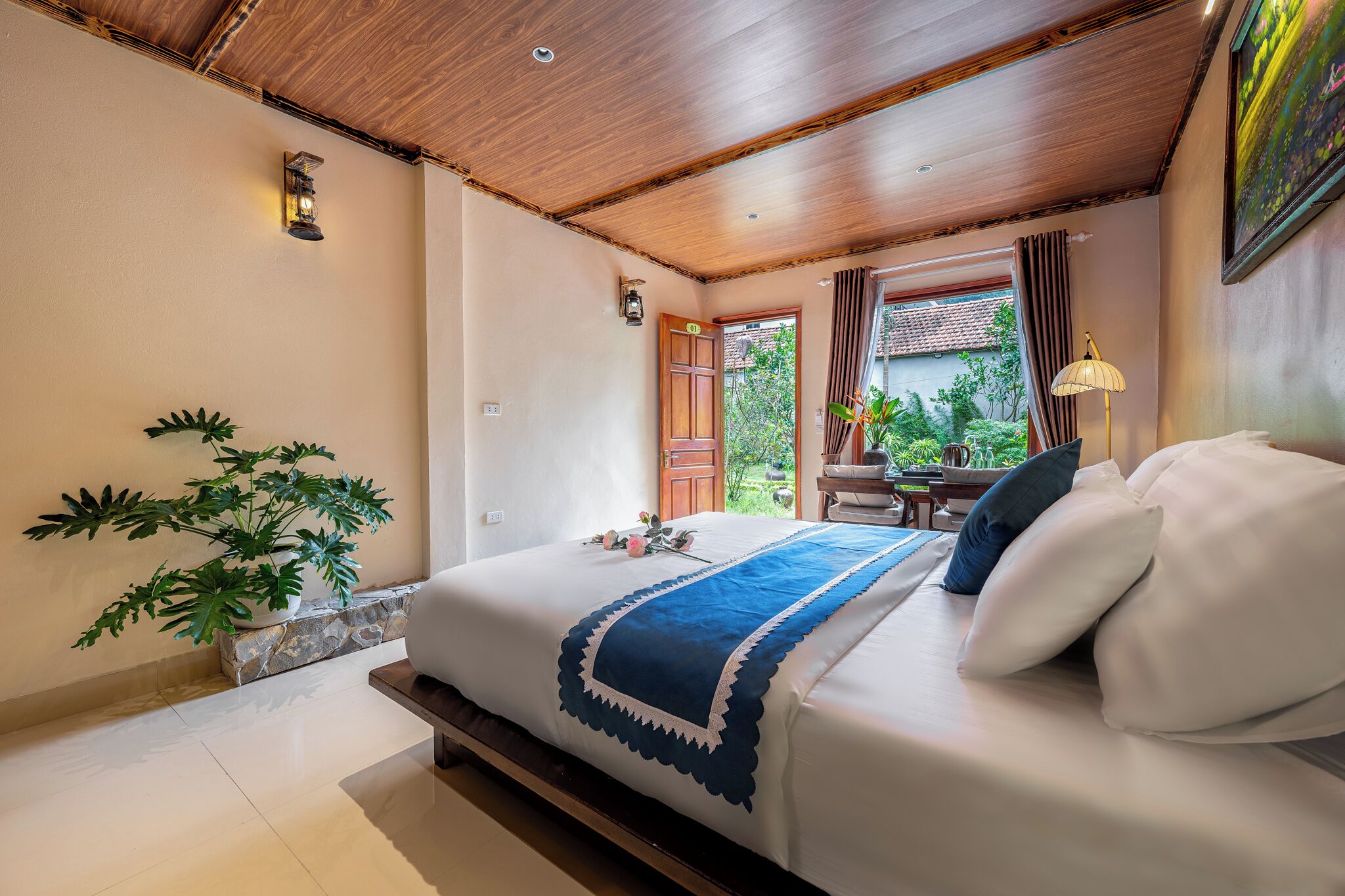 Un dormitorio con una cama, una planta en maceta, una mesita de noche y una ventana con cortinas.