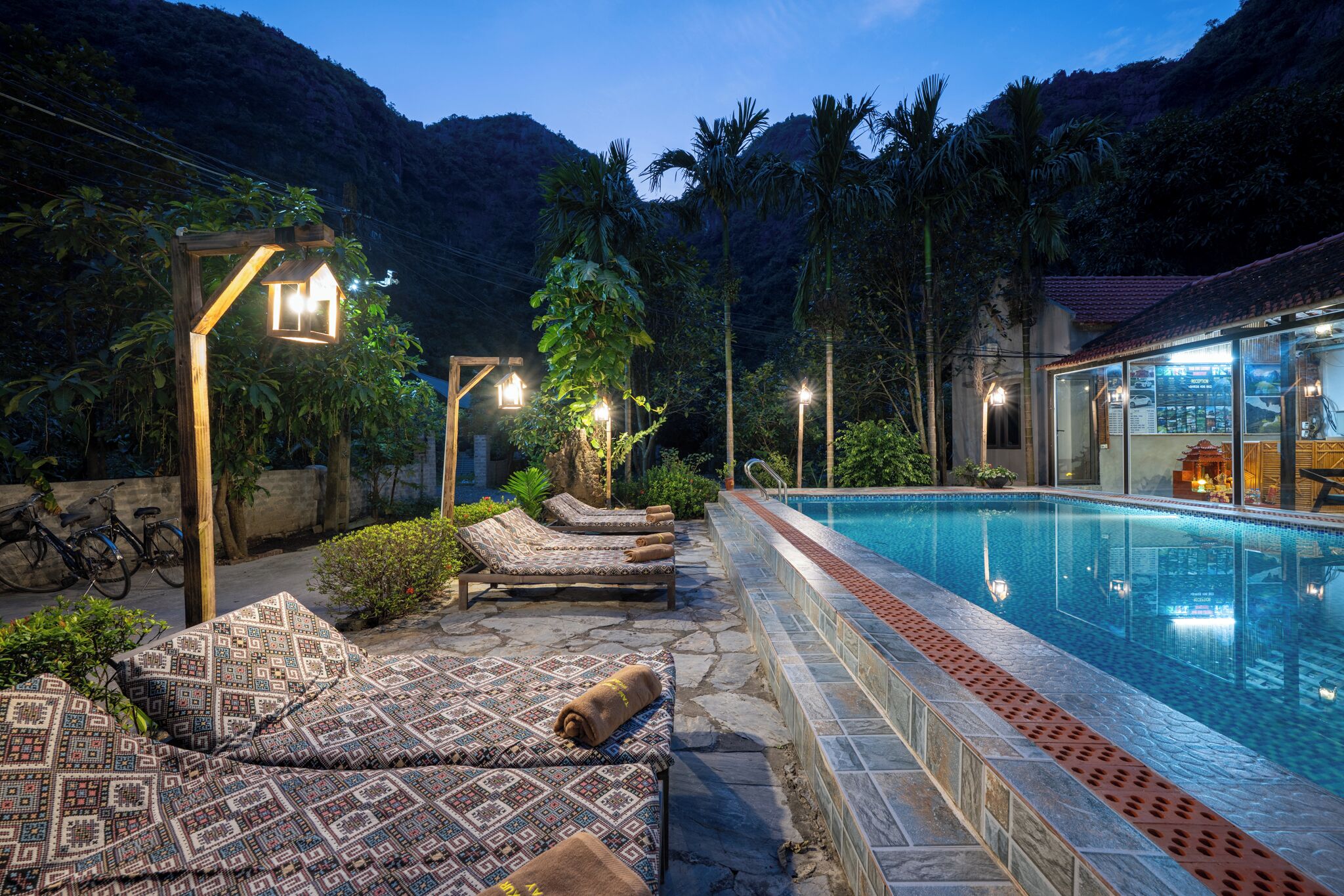 A poolside area with lounge chairs, a swimming pool, and a restaurant with outdoor seating.
