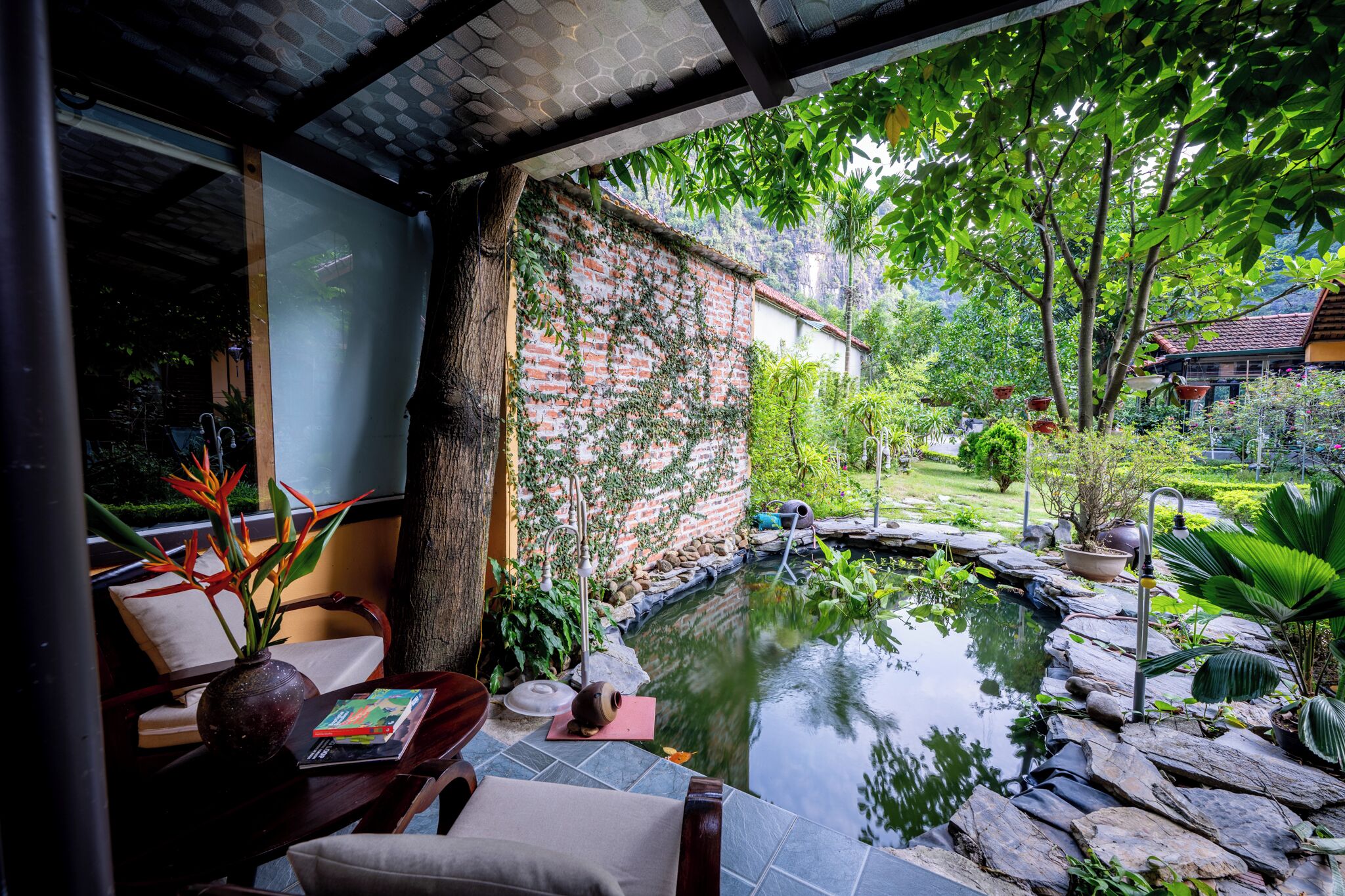 A serene outdoor area with a pond, stone pathway, and lush greenery.