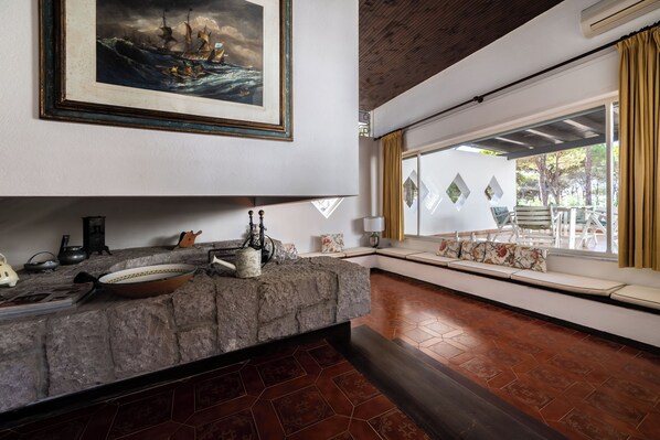 Um quarto espaçoso com bancada de pedra, uma janela ampla com vista e um quadro na parede.