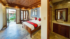A hotel room with a wooden ceiling, a large bed with red and black bedding, a stone-tiled floor, and a stone wall. - Green Grapefruit Villa (Da Nang)