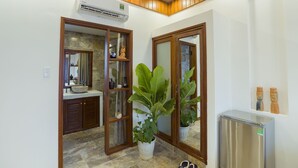 A bathroom with a stone sink, wooden cabinets, a potted plant, and a refrigerator. - Green Grapefruit Villa (Da Nang)