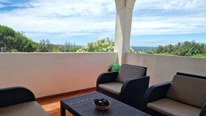 A balcony with wicker furniture, a small table, and a view of the sea. - Villa with large pool, mountain&ocean view-near beaches&Lisbon  (Sesimbra)
