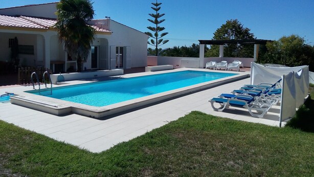 A rectangular swimming pool with a tiled deck, surrounded by a white fence and blue lounge chairs. - Villa with large pool, mountain&ocean view-near beaches&Lisbon  (Sesimbra)