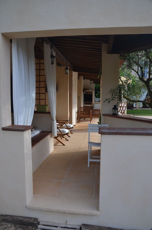 A covered outdoor seating area with chairs and a table, a wooden bench, and a view of a garden. - mansion - PIGNANS (Pignans)
