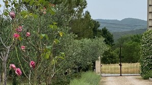 Un camino de grava que conduce a una entrada con puerta y vistas de un paisaje montañoso.