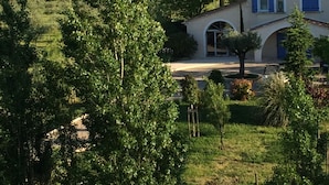 Una casa con techo de tejas, un pequeño arco y un camino de entrada pavimentado.