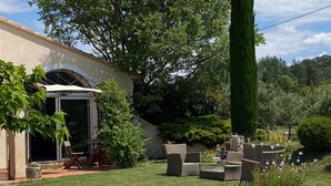 Un jardín cuidado con un área de patio, mobiliario exterior y una variedad de plantas.