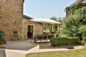 An outdoor patio with stone walls, a table with chairs, and a large umbrella. - Beautiful Perigourdine house 12 km from Sarlat, Montignac-Lacaux, Les Eyzies (Tamniès)