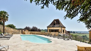 A pool area with lounge chairs, a stone wall, and a view of the countryside. - Beautiful Perigourdine house 12 km from Sarlat, Montignac-Lacaux, Les Eyzies (Tamniès)