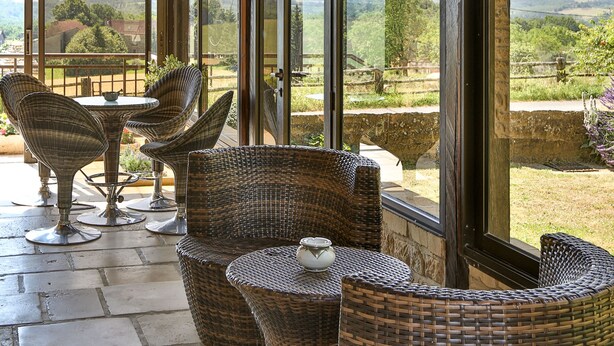 A covered outdoor seating area with wicker furniture and large windows offering a view of the countryside. - Beautiful Perigourdine house 12 km from Sarlat, Montignac-Lacaux, Les Eyzies (Tamniès)