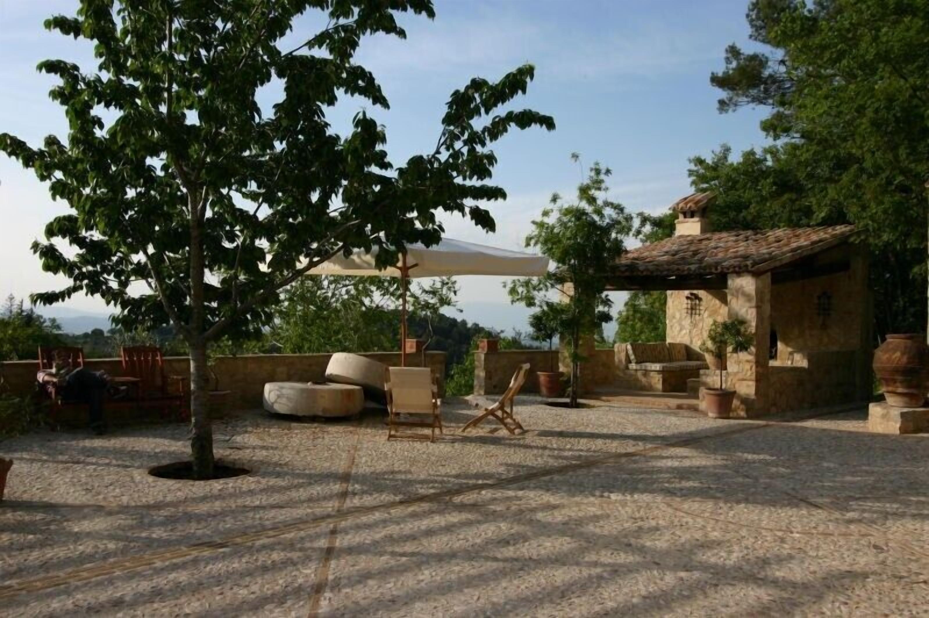 An outdoor patio area with stone flooring, a large umbrella, and rustic stone walls.