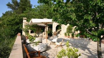 An outdoor patio area with stone flooring, wooden furniture, and potted plants.