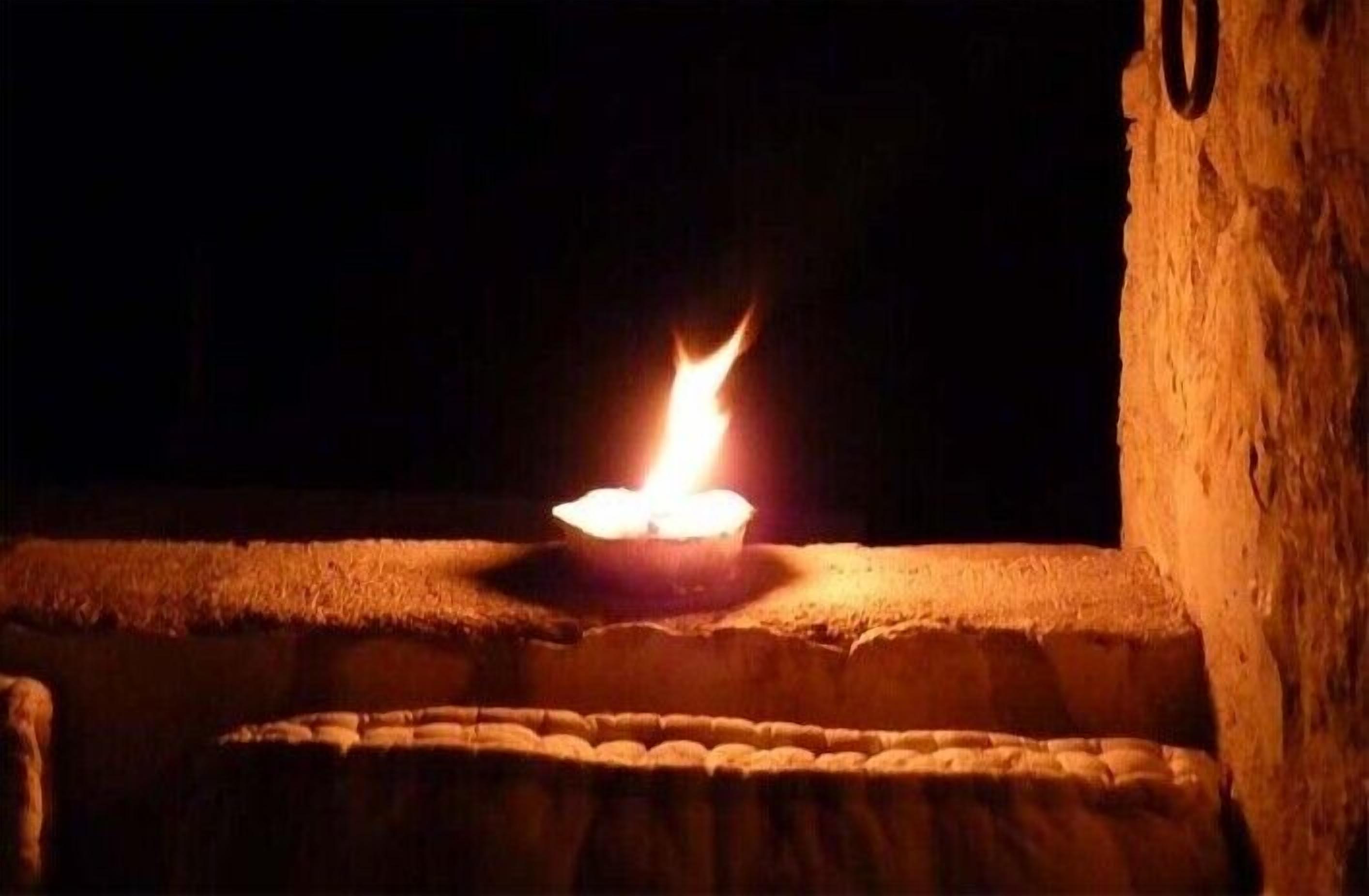 A lit candle on a stone ledge.