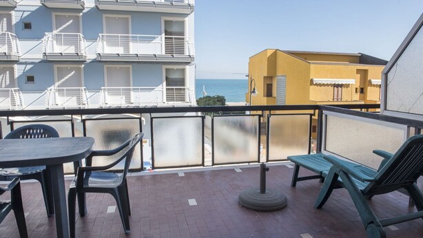 A balcony with a table and chairs, a round table, and a bench. - M029 - Marcelli, new seafront two-room apartment with terrace (Marcelli)