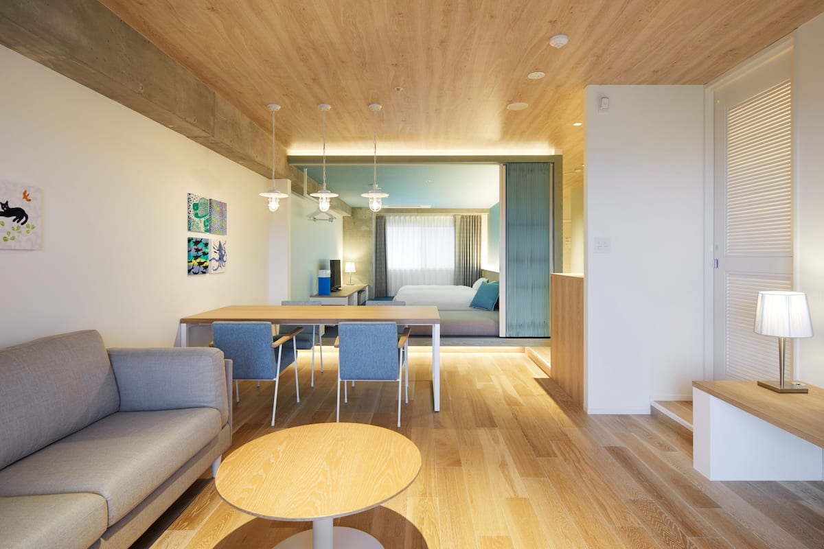 Une chambre d’hôtel moderne avec un plafond en bois, un coin repas doté d’une table ronde, un canapé et un lit offrant une vue agréable.