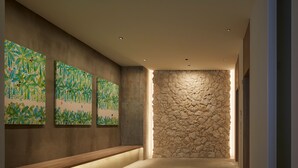 A hallway with a stone wall, wooden bench, and three framed artworks on the wall.