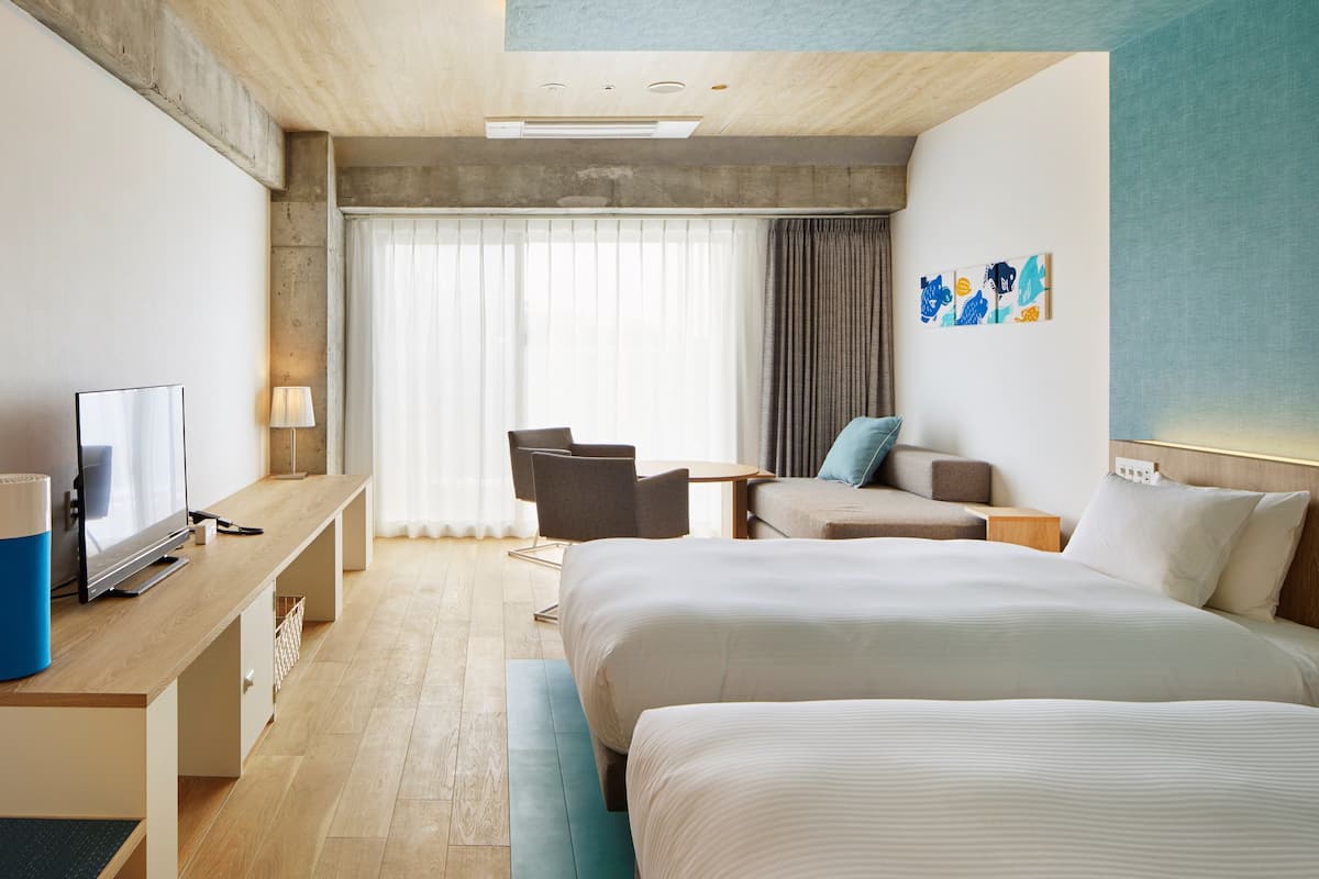 Une chambre d’hôtel moderne avec un grand lit, un bureau avec une télévision, une chaise et une petite table.