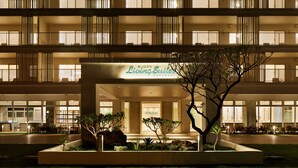 A multi-story hotel with a modern design, featuring balconies with metal railings and a well-lit entrance.