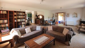 Ein gemütliches Wohnzimmer mit einem braunen Sofa, einem Holztisch und einem Bücherregal voller Bücher.