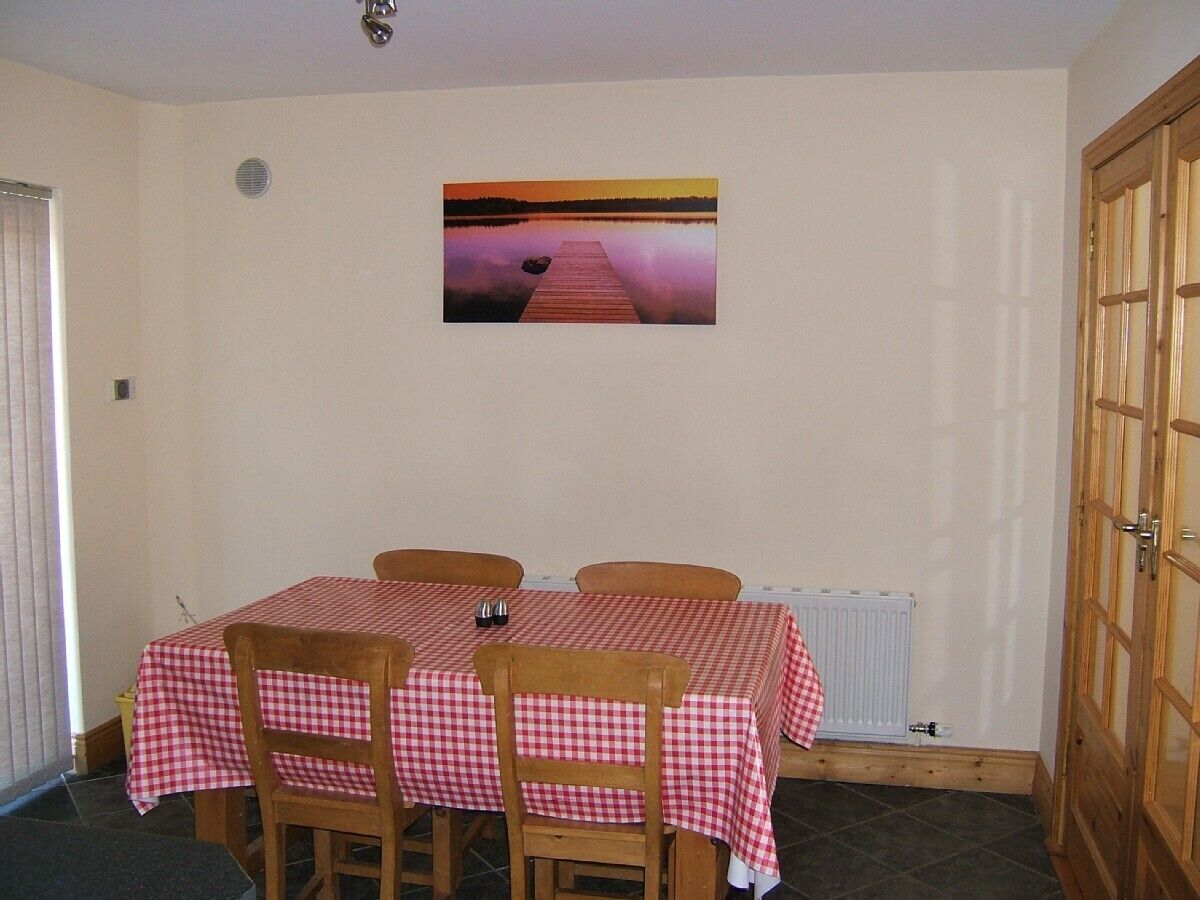 A dining area with a table set for two, a wooden chair, and a picture on the wall.