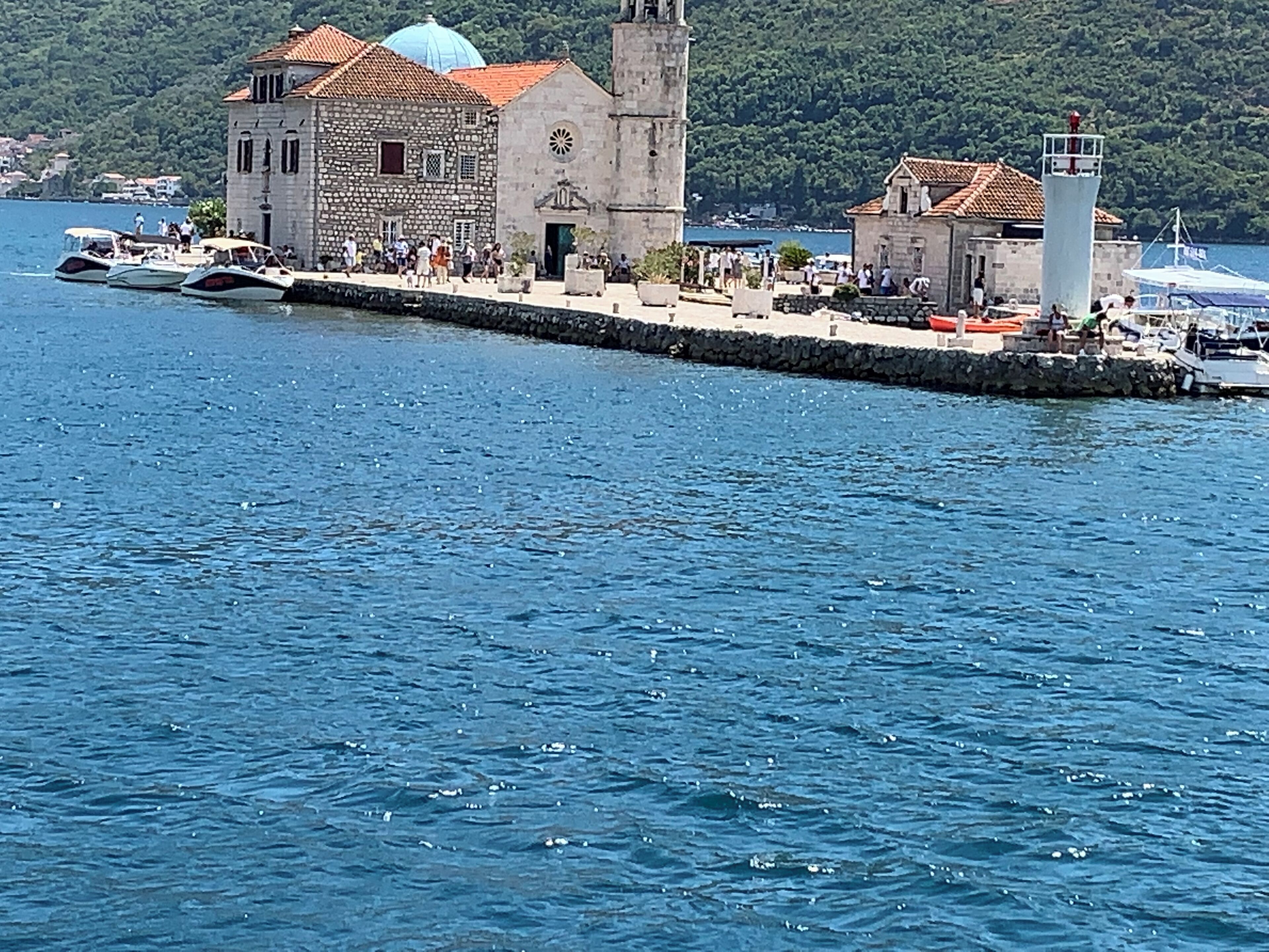 Un pueblo costero con un edificio de piedra destacado que incluye una torre de campanas y un faro.