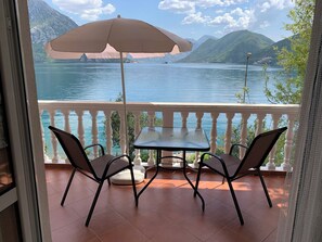 A balcony with a table and chairs, overlooking a lake with mountains in the background. - B unit, One bedroom, Stunning views, waterfront, free secured parking (Lipci)