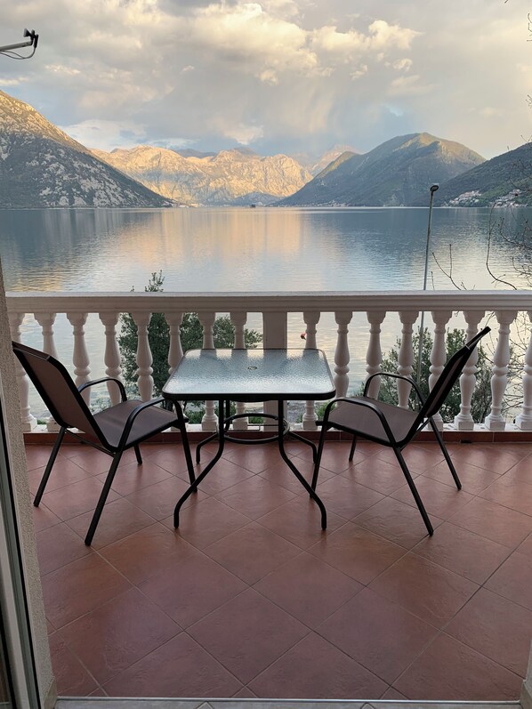 A balcony with a table and two chairs overlooking a lake with mountains in the background. - B unit, One bedroom, Stunning views, waterfront, free secured parking (Lipci)