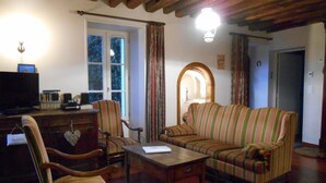 A cozy living room with wooden beams, a television, striped armchairs, and a sofa. - Gîte Suzanne, in Essonne Verte, near Milly la Forêt (Brouy)