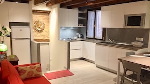 Una cocina compacta con armarios blancos, estufa a gas y microondas.