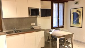 Una cocina moderna con armarios blancos, un microondas y una zona de comedor con mesa y sillas.