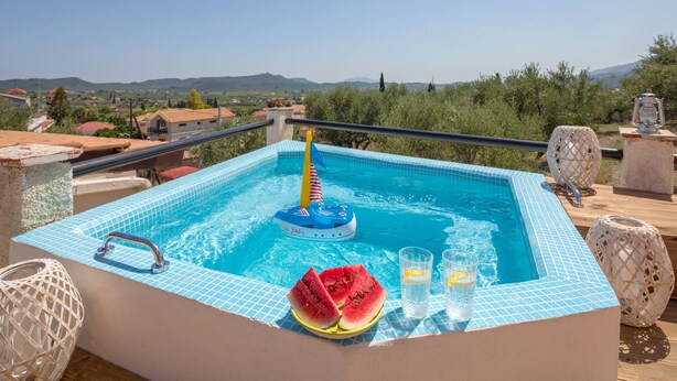 Ein Schwimmbecken mit Blick auf die Landschaft, ein schwimmendes Spielzeug und eine Wassermelonenscheibe.