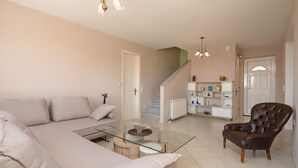 Ein Wohnzimmer mit Sofa, Sesseln, einem Glastisch und einer Treppe zu einer weiteren Ebene.