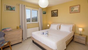 Ein Schlafzimmer mit Bett, Nachttischen, einem Schminktisch, einem Fenster mit Vorhängen und Bildern an den Wänden.