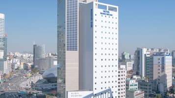 A high-rise hotel with a modern design, located in a busy urban area with surrounding buildings and a clear sky.