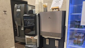 A coffee machine with an ice dispenser and a beverage dispenser, next to a refrigerator with a beverage display. - Toyoko Inn Seoul Dongdaemun No.2 (Seoul)